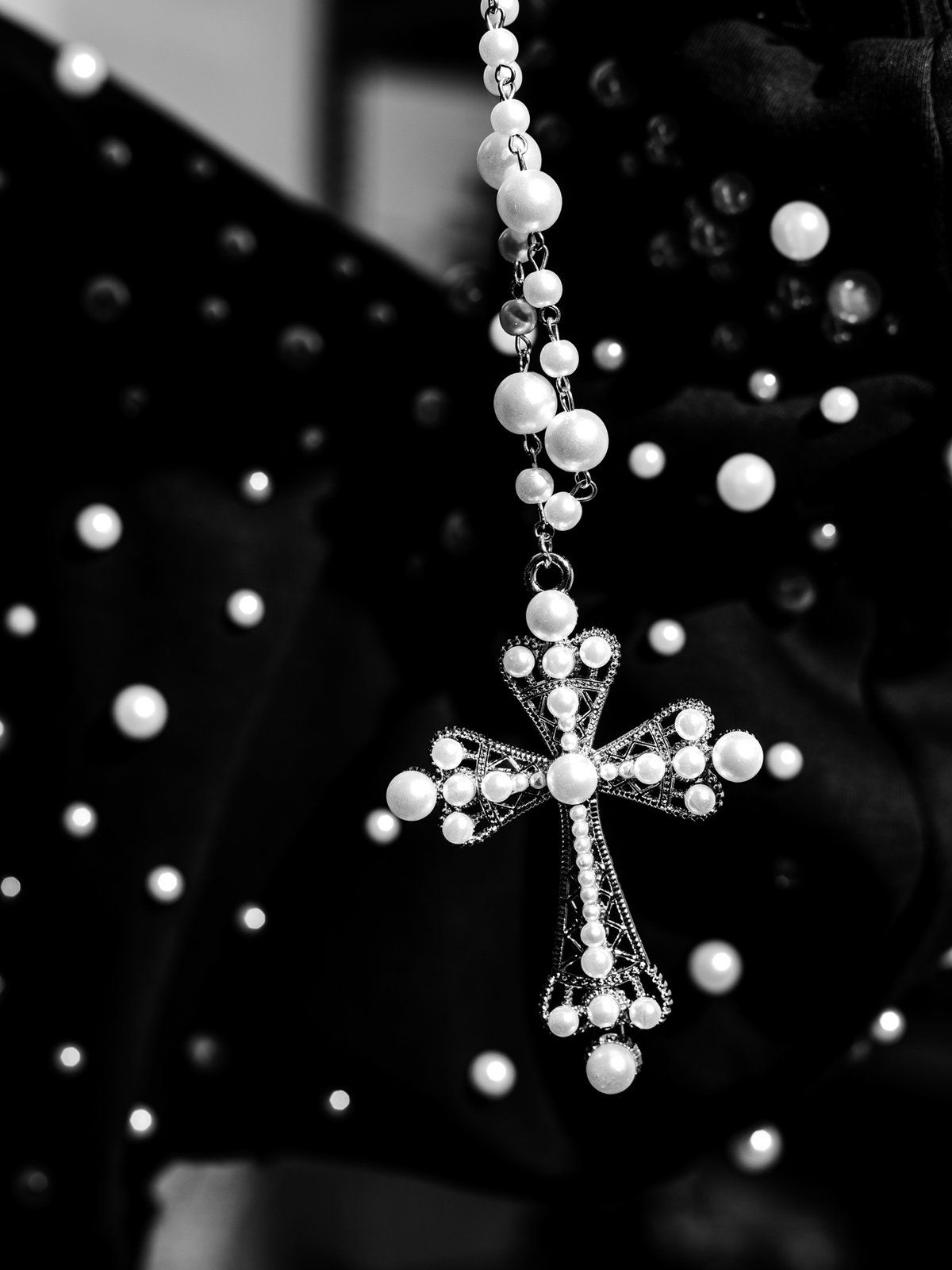 Pearl cross necklace hanging over a pearl zip-up