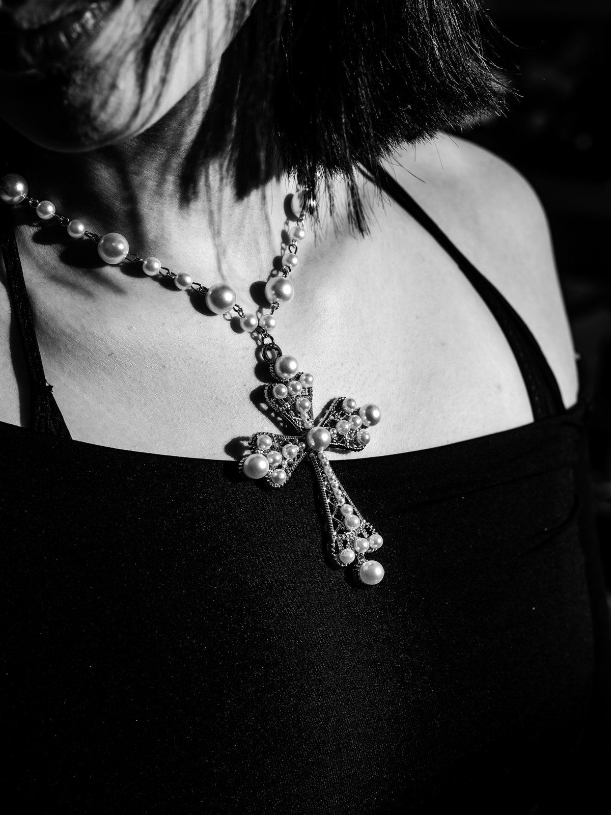 Pearl cross necklace worn over a black top