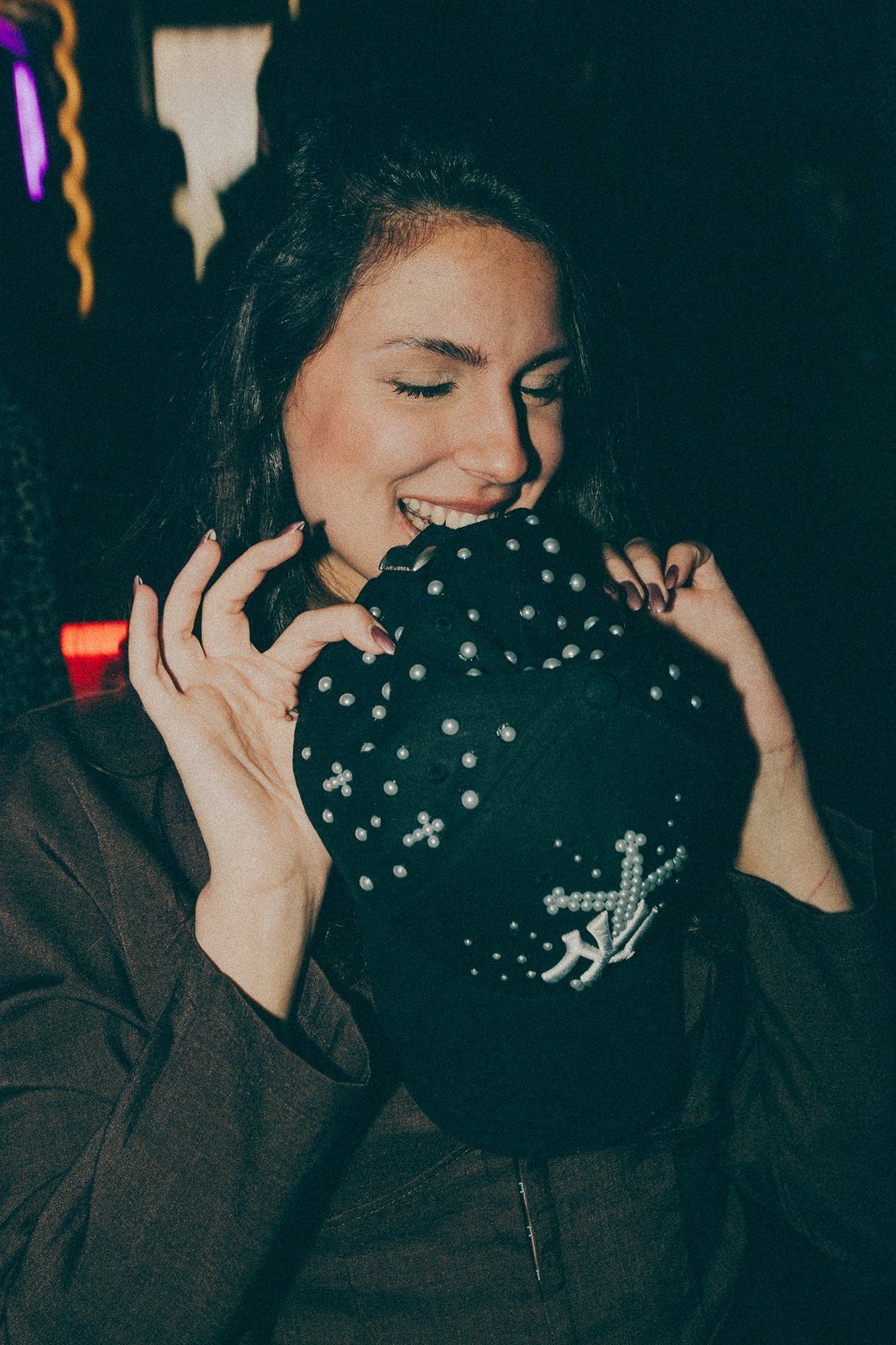 Pearl black cap held over the face at a party
