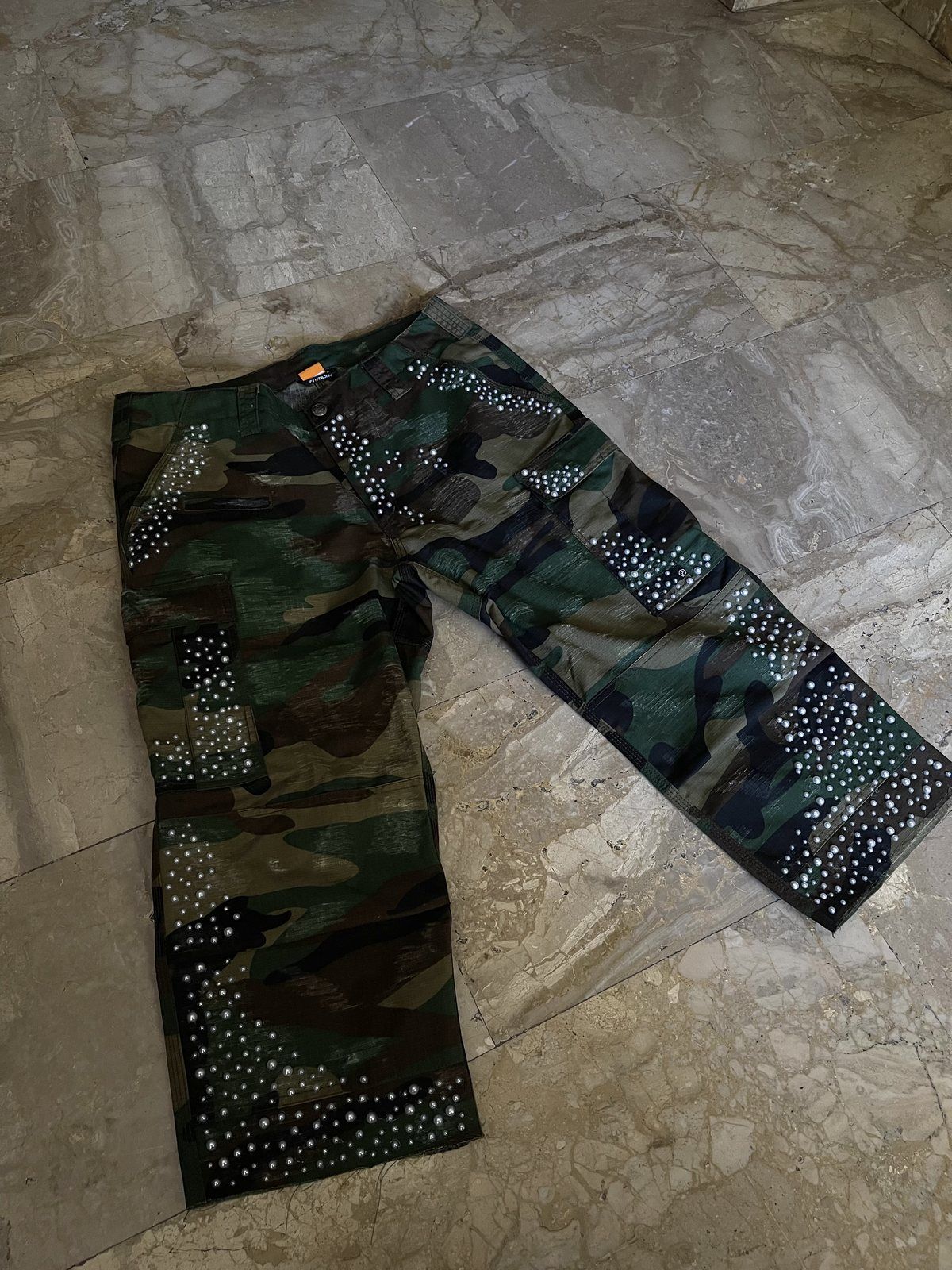 Camo military pants with pearls laid flat on stone