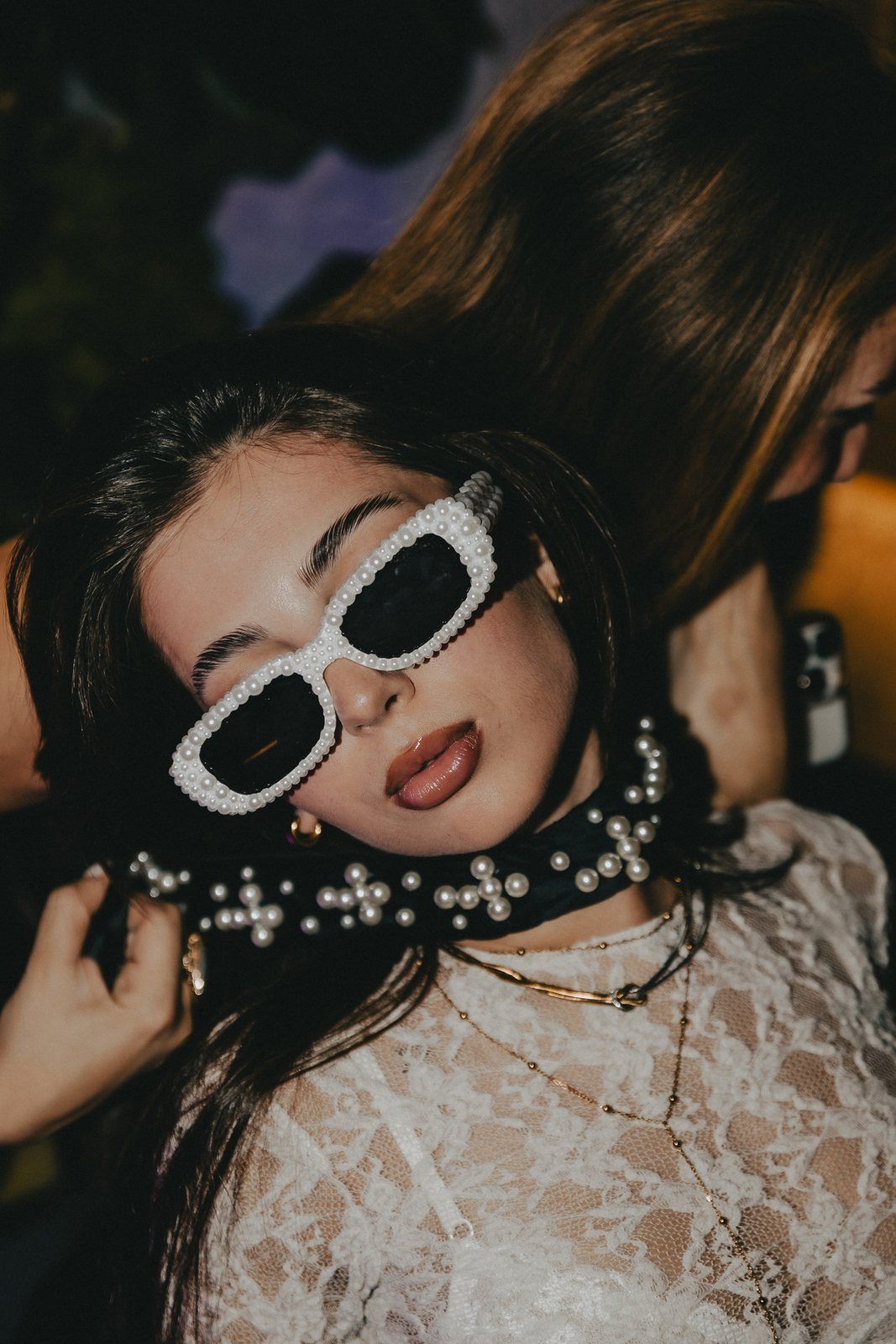 Pearl tie wrapped round the neck, worn with white sunglasses