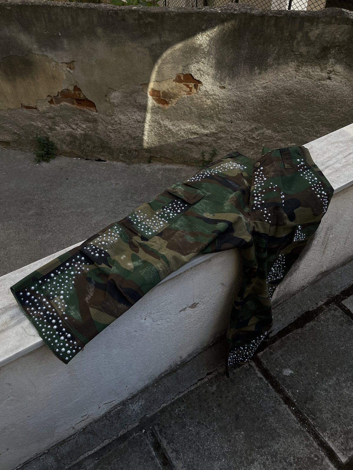 Camo military pants with pearls hanging over a wall
